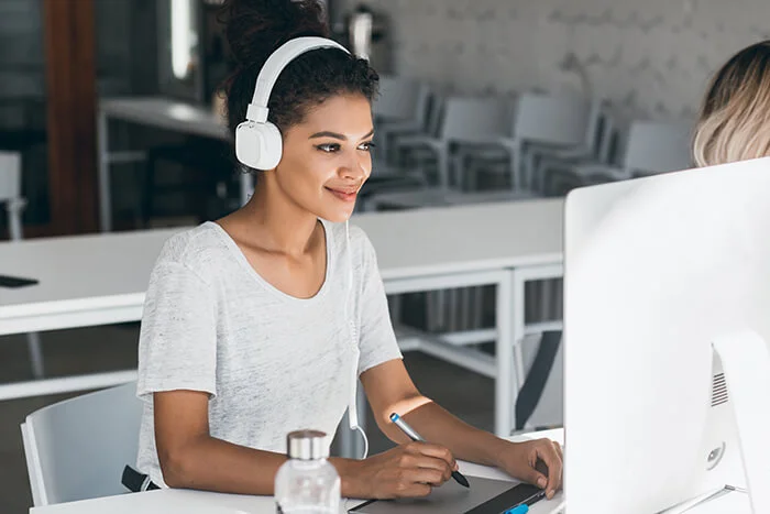 elegant-african-web-designer-doing-her-job-office-with-smile-attractive-black-woman-white-headphones-working-call-center-sitting-near-computer-1
